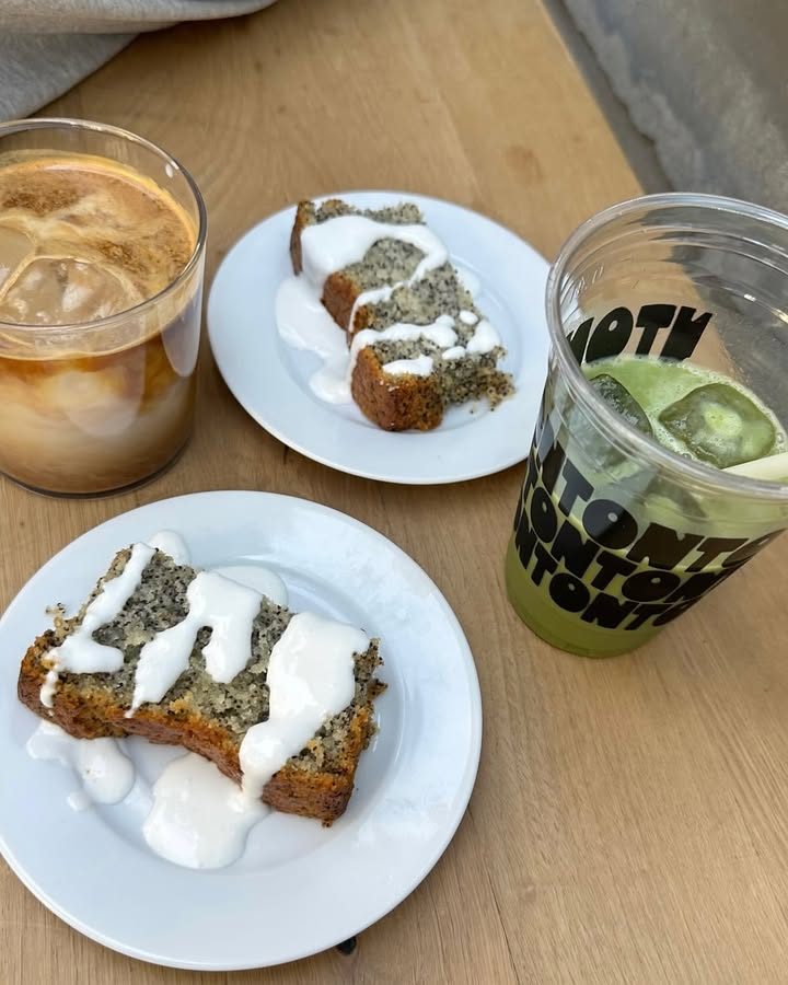 Two slices of loaf cake with icing, next to an iced coffee and an iced matcha