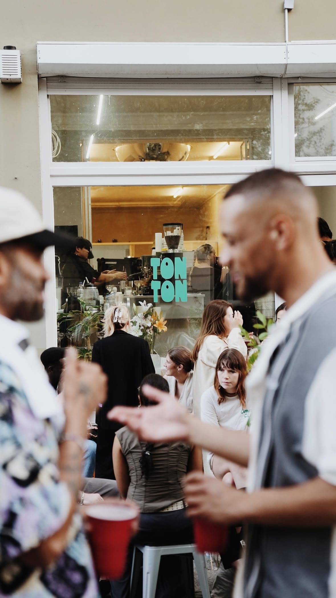 A crowd on the pavement outside the TON TON window, cups in hand