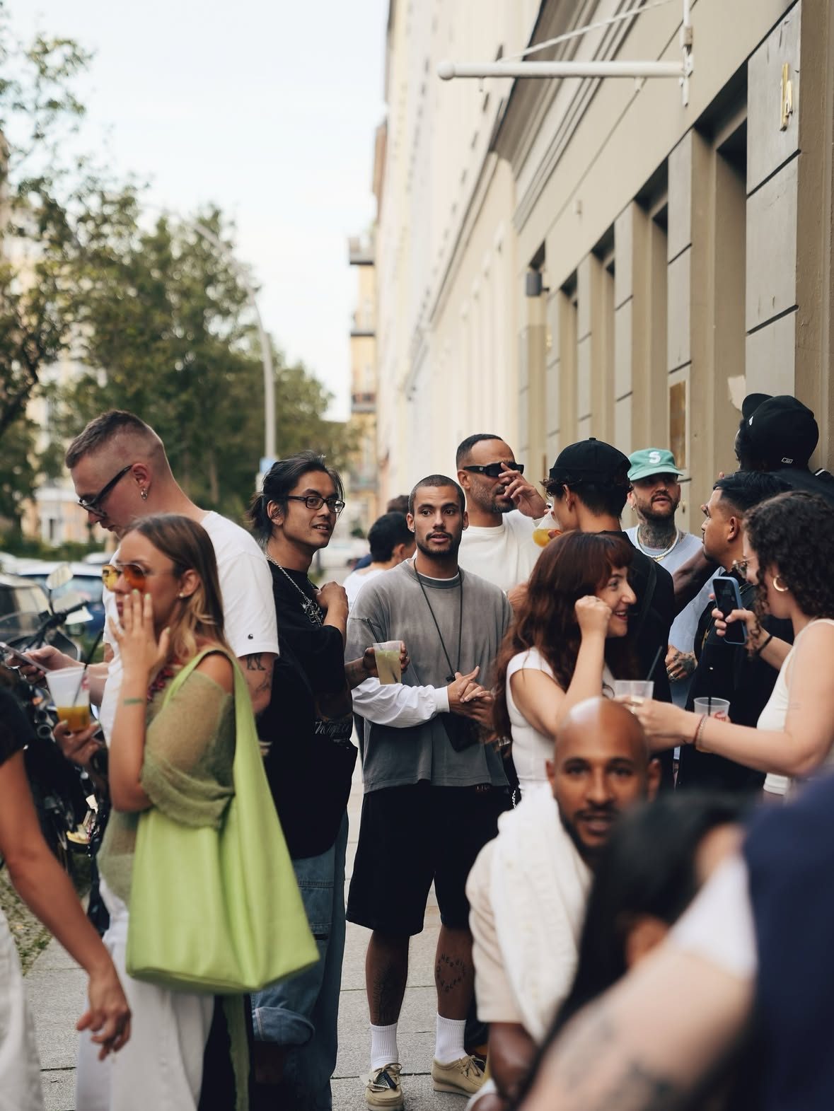 A crowd with drinks on the pavement outside the café at the Clarks gathering