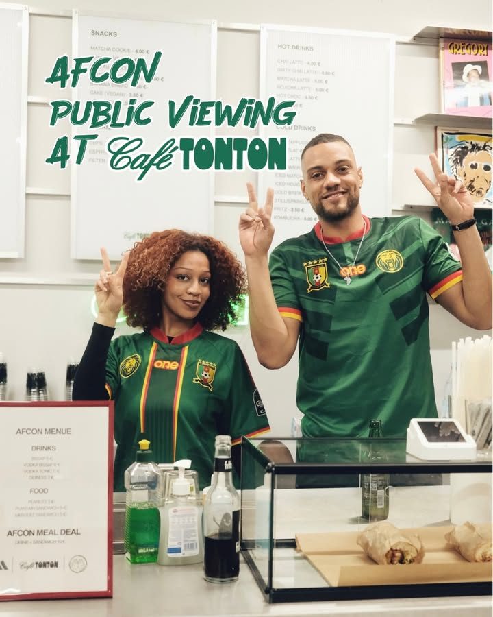Two people in green jerseys making peace signs behind the café counter