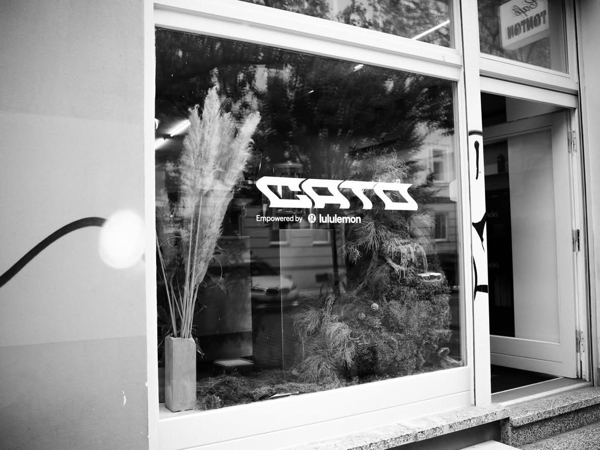 The café window in black and white with the CATO, empowered by lululemon decal
