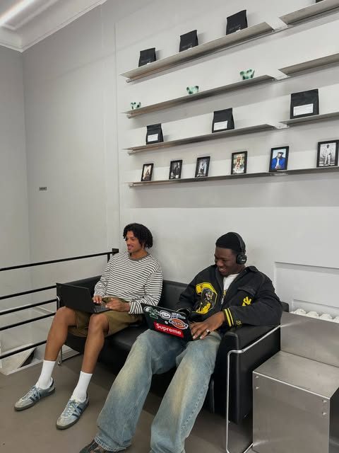 Two people on the black sofa, one working on a laptop
