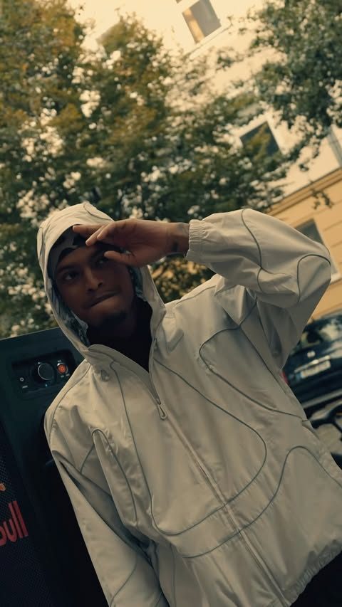 A runner in a pale jacket by a speaker after the Sunday run, one hand raised to his cap.